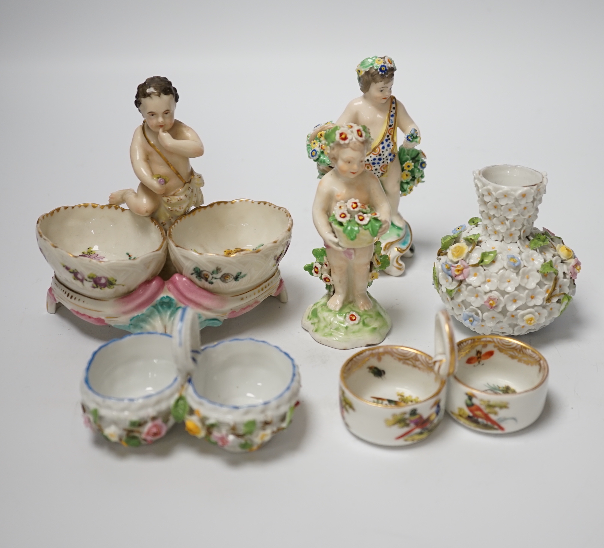 A group of German flower encrusted tableware, including a matched Meissen cup and saucer, lidded box, salts, figures, etc., tallest figure 12cm